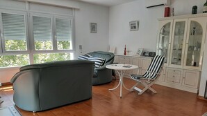 Ein Wohnzimmer mit einer Couch, einem Sessel, einem kleinen Tisch und einem Schrank.