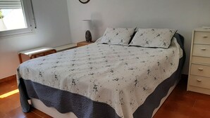 Ein ordentlich gemachtes Bett mit floralem Überwurf und blauem Akzent am Fußende.