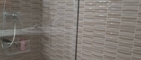 A shower area with a white shower seat and a glass partition.