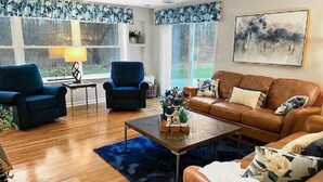 A living room with a brown leather sofa, two blue armchairs, a coffee table, and a lamp. - Heron Pointe... where nature and luxury combine for an unforgettable experience! (White Lake)