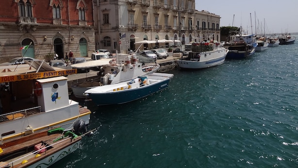 A marina with several boats docked alongside a historic building with arched windows and balconies.