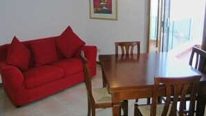 A dining area with a red sofa, wooden table, and chairs.