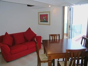 Ein Essbereich mit rotem Sofa, Holztisch und Stühlen.
