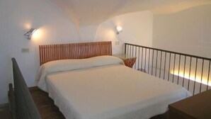 A bedroom with a bed, a wooden headboard, a nightstand, and two wall-mounted lights.