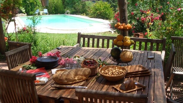 Un área de comedor al aire libre con una piscina al fondo.