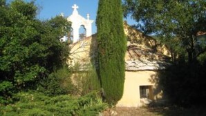 A building with a cross on top, surrounded by greenery. - Stone house of character in a typical Provencal hamlet (Banon)