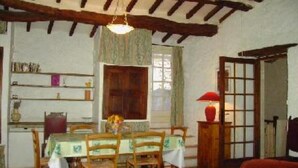A dining room with wooden furniture, a table with a tablecloth, and a hanging light fixture. - Stone house of character in a typical Provencal hamlet (Banon)