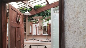 A bathroom with a wooden door, a sink, and a mirror. - House with character, rustic style House with garden, weekly rental  (Locoal-Mendon)