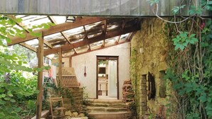 A rustic wooden structure with a metal roof, a stone staircase leading to a door, and a green artificial turf area. - House with character, rustic style House with garden, weekly rental  (Locoal-Mendon)