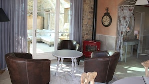 Un salon chaleureux avec des fauteuils en cuir, une table ronde et un mur en pierre.