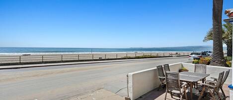 A patio with a table and chairs overlooking a beach.
