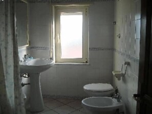 A bathroom with a sink, toilet, and bidet. There is a window above the toilet. - Sardinia - Cala Gonone (Nuoro) – Sea & Mountain – 80m Away From The Sea. (Cala Gonone)
