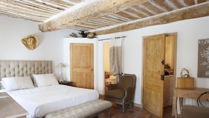 A bedroom with a large bed, wooden doors, a chair, and a small table. - House / Villa - Collobrières (Collobrières)