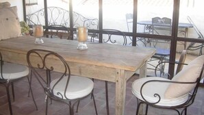 A wooden table with four chairs, two candles, and a view of a balcony with outdoor furniture. - House / Villa - Collobrières (Collobrières)