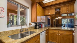 A kitchen with granite countertops, wooden cabinets, a stainless steel sink, and a dishwasher. - Yosemite Vista (Yosemite National Park)
