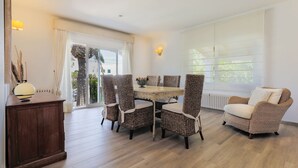 Un comedor con sillas de mimbre, una mesa de madera y un sofá.