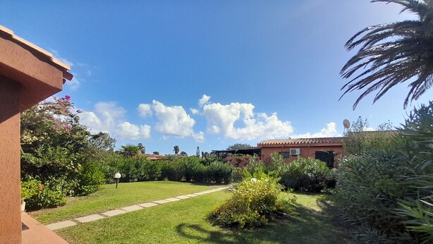 A well-maintained garden with a paved pathway leading to a building with a tiled roof.