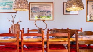 A dining area with a wooden table and chairs, framed artwork on the wall, and woven pendant lights. - Costabravaforrent Masramon (l'Escala)