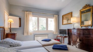 A hotel room with two beds, a desk, a dresser, a TV, and a window with curtains. - Costabravaforrent Masramon (l'Escala)