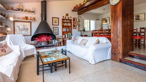 A cozy living room with a fireplace, white furniture, and a wooden ceiling. - Costabravaforrent Masramon (l'Escala)