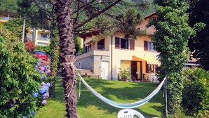 Une maison avec une façade en pierre, un escalier apparent et un hamac dans la cour.