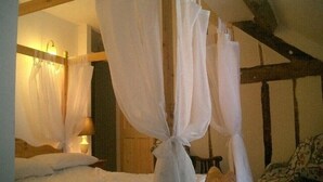 Une chambre à coucher avec un lit à baldaquin, du linge de lit blanc et un plafond en bois.