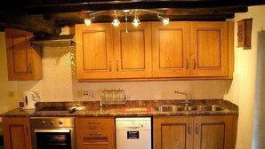 Une cuisine dotée de meubles en bois, d’un four encastré, d’un lave-vaisselle et d’un plan de travail en granit.
