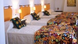A hotel room with a high ceiling, exposed wooden beams, and a series of beds with floral-patterned bedspreads. - Andalucia Center. Beautiful house (ENCINAS REALES)