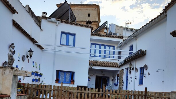 A courtyard with a swimming pool, white buildings with blue windows, and a wooden fence. - Andalucia Center. Beautiful house (ENCINAS REALES)