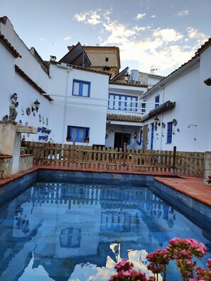 A courtyard with a swimming pool, white buildings with blue windows, and a wooden fence. - Andalucia Center. Beautiful house (ENCINAS REALES)