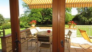Eine Terrasse im Freien mit einem runden Tisch, Stühlen und Blumentöpfen.