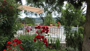 Ein Garten mit roten Blumen und einer Pergola.