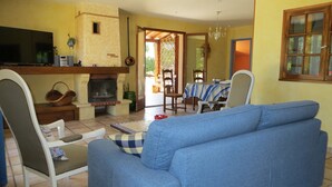 Ein Wohnzimmer mit Sofa, Fernseher, Kamin und einem Essbereich mit Stühlen und Tisch.