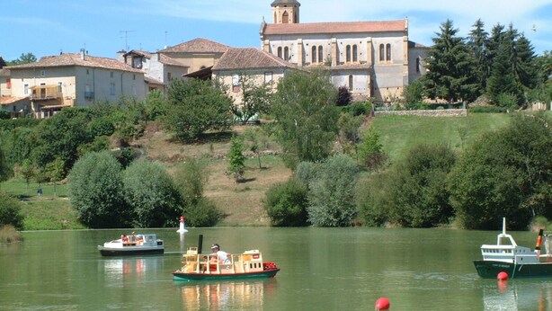 Ein Fluss mit Booten, einer Kirche und Wohnhäusern.