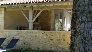 A stone-walled outdoor seating area with a pergola overhead.
