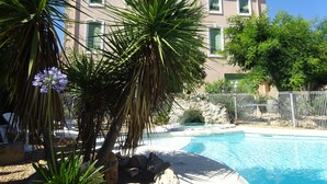 Una piscina circondata da palme e un edificio con tetto in tegole.