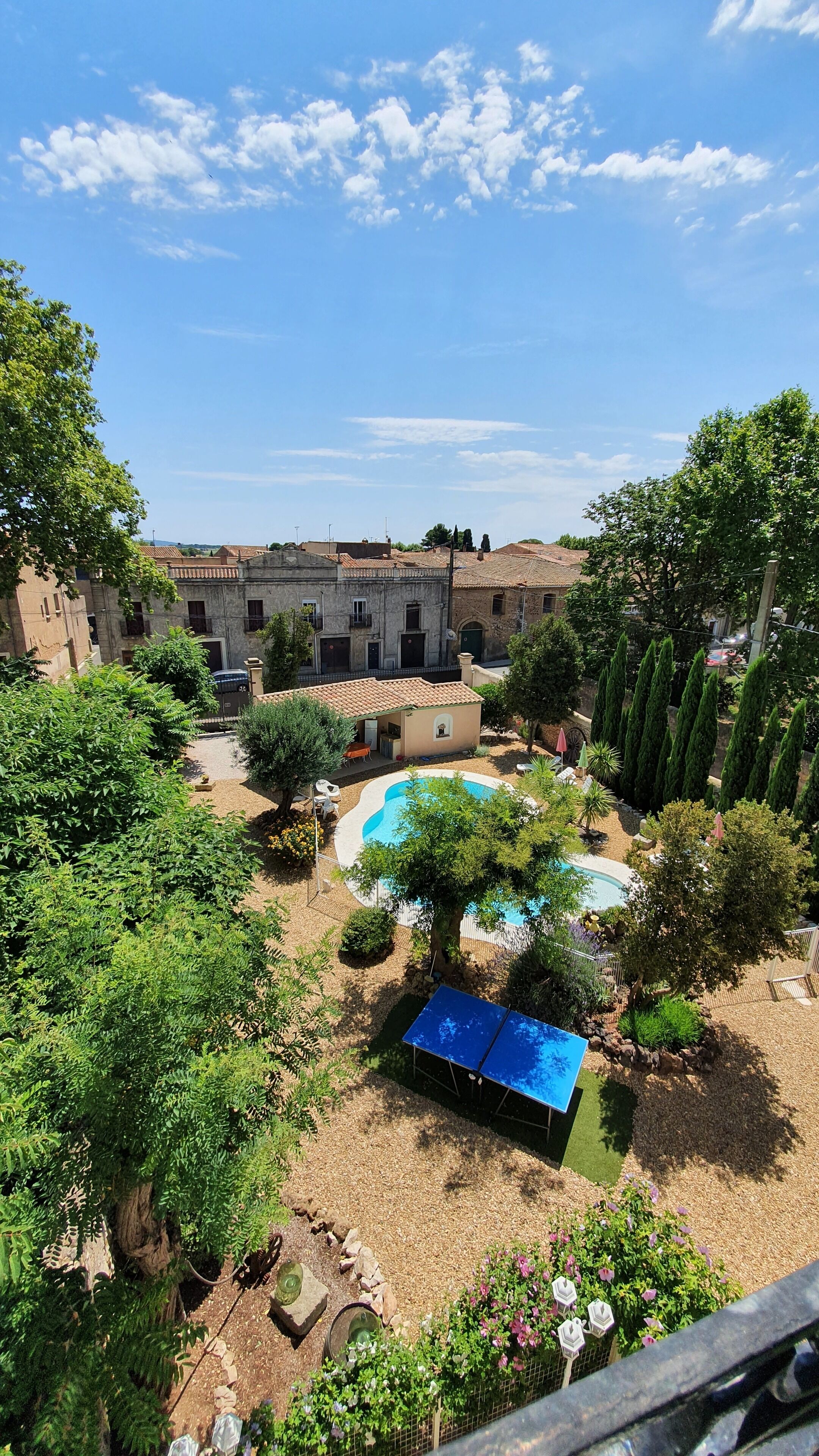 Une cour avec une piscine, un court de tennis et un bâtiment doté de nombreuses fenêtres.
