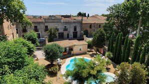 Un cortile con piscina, campo da tennis e un edificio con numerose finestre.