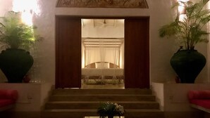 A hotel lobby with a large vase, a coffee table, and a staircase leading to a bedroom.