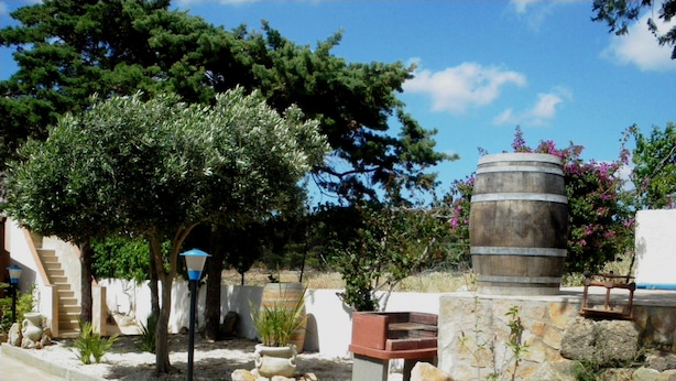 Un patio con un banco de piedra, un barril de madera y una escalera que lleva a un edificio.
