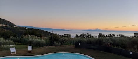 A swimming pool with a view of the sea and hills.