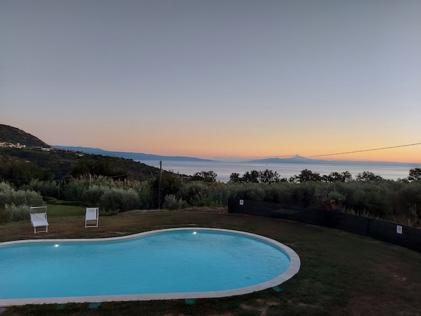 A swimming pool with a view of the sea and hills.