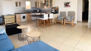 Una cocina moderna con comedor, un sofá y dos sillones mecedoras.