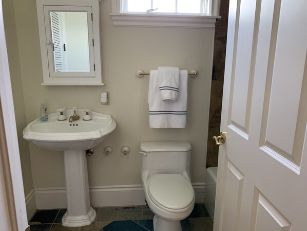A bathroom with a pedestal sink, a toilet, and a towel rack.