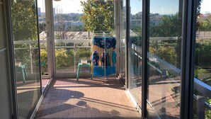 A balcony with a view of the city, a small table, and a chair. - Air conditioning, welcome pack, 3 bedroom, 2 bathroom, pool, tennis, parking (Antibes)