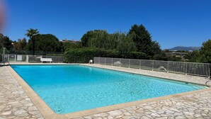 A rectangular swimming pool with a stone border, surrounded by a white fence and a bench. - Air conditioning, welcome pack, 3 bedroom, 2 bathroom, pool, tennis, parking (Antibes)