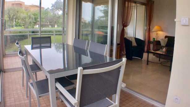 A glass-enclosed dining area with a table and chairs, a sofa, and a lamp. - Air conditioning, welcome pack, 3 bedroom, 2 bathroom, pool, tennis, parking (Antibes)