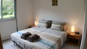 A neatly made bed with striped bedding and pillows, two bedside tables with lamps, and an air conditioning unit on the wall. - Air conditioning, welcome pack, 3 bedroom, 2 bathroom, pool, tennis, parking (Antibes)