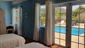 Un dormitorio con cama, armario y vistas a una piscina y zona de estar exterior.
