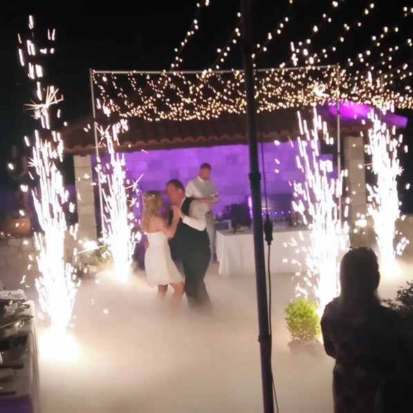 A wedding ceremony with a decorated arch and sparklers.
